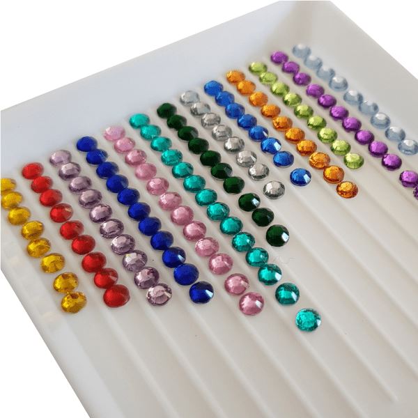 Bunte Glitzersteine in einer weißen Sortierschale für Diamond Painting und Bastelprojekte